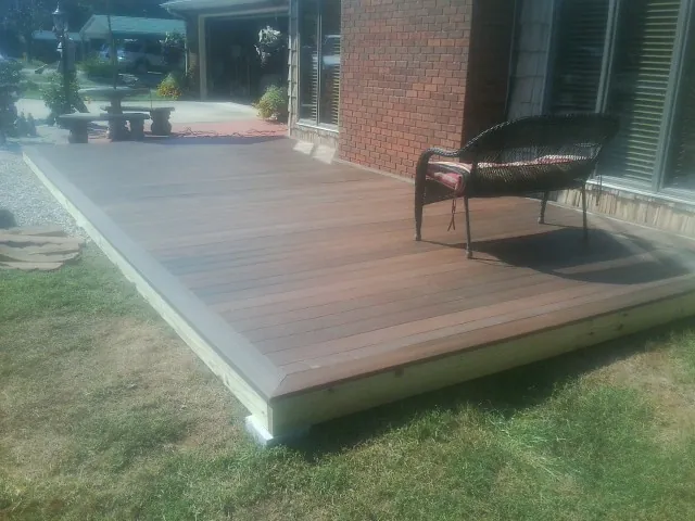 New wood deck and wicker chair beside a brick house in Marion