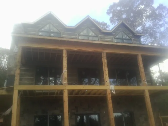 Dormers and porch framing on a large log home under construction — Roof Coating work by our crew in Marion